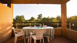 A covered outdoor dining area with a table set for two, surrounded by chairs, overlooking a lush green landscape. - Marina Corsa Residence 3rooms apartment 150 m from the beach - Ghisonaccia (Ghisonaccia)