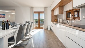 Eine moderne Küche mit weißen Schränken, einer Holz Arbeitsplatte und Blick ins Freie.