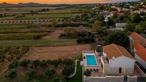 Eine Villa mit Schwimmbad, umgeben von Weinbergen und einem Dorf.