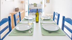 A dining area with a white table set for two, blue chairs, and a view through an open door to the outside. - Beach House with Seaview (Naxos)