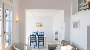 A living room with a sofa, a dining table with chairs, and a hanging light fixture. - Beach House with Seaview (Naxos)