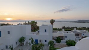 A coastal view with white buildings, a sunset, and a body of water. - Beach House with Seaview (Naxos)