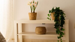 Een plank met twee gevlochten manden, waarvan één bloemen bevat en de andere groen loof.
