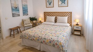 Een slaapkamer met een bed, twee nachtkastjes, een stoel, een hanglamp en wanddecoratie.