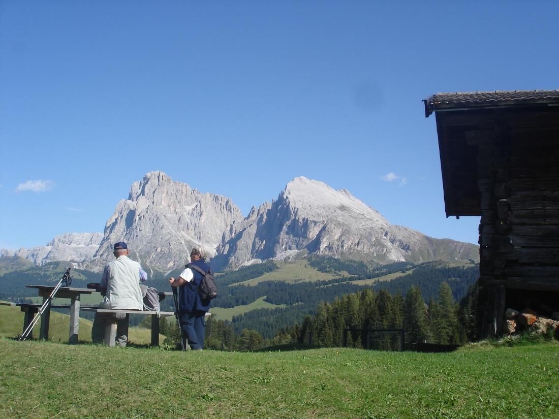 A mountain lodge with a wooden exterior, a picnic table, and a clear view of the surrounding mountains.