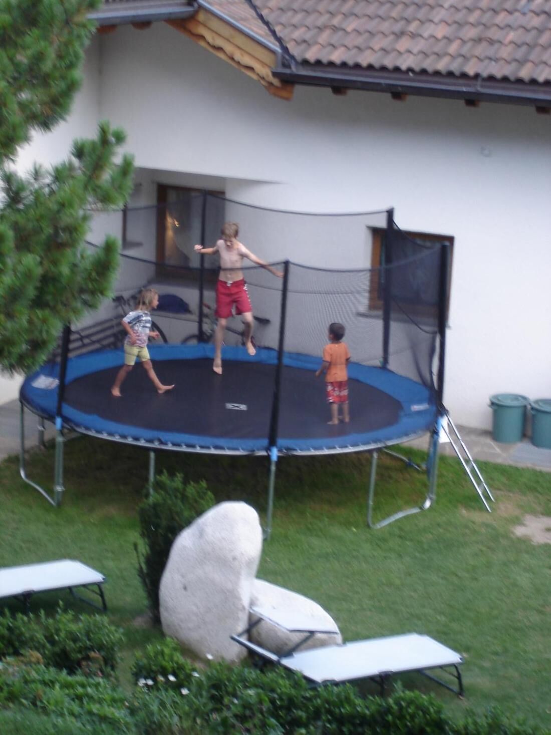 A trampoline in a backyard with a house in the background.