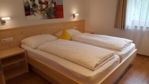 A double bed with a wooden headboard, a bedside table, and a wall-mounted light.