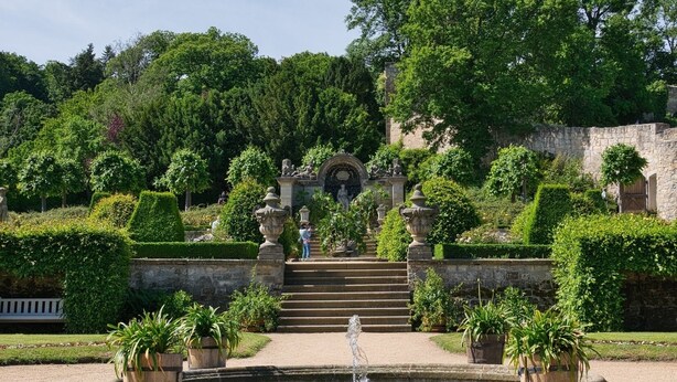 Un jardin à la française agrémenté d’une fontaine, d’escaliers en pierre et de statues.