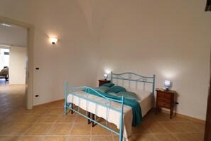Une chambre à coucher avec un lit, des tables de chevet et un luminaire fixé au mur.