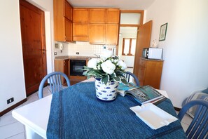 Una cucina con mobili in legno, un forno a microonde e un tavolo da pranzo con sedie.