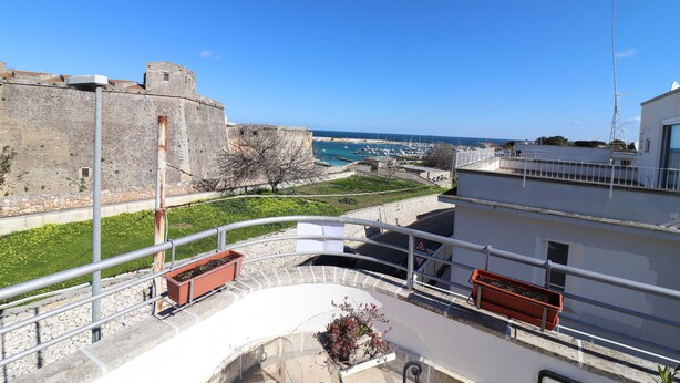 Un balcón con vista a una fortaleza histórica y un puerto deportivo.
