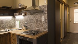 Una cocina con estufa, pileta y diversos utensilios.