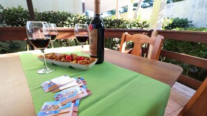 Une table avec une bouteille de vin, deux verres de vin rouge, une assiette de collations et quelques brochures.