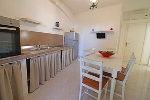 Una cucina con piano cottura, forno, frigorifero e un tavolo da pranzo con sedie.