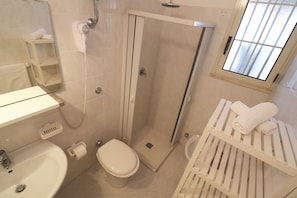 Une salle de bain Ă©quipĂ©e dâune douche, de toilettes, dâun lavabo et dâun porte-serviettes.
