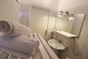 Une salle de bain avec un lavabo blanc, un miroir et une serviette sur un porte-serviettes blanc.