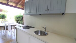 Una cocina con un lavamanos de acero inoxidable, armarios blancos y techo de madera.