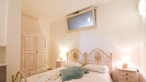 Een slaapkamer met een bed, twee nachtkastjes, een aan de muur bevestigde televisie en een kledingkast.