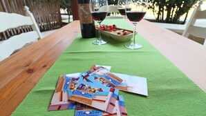 Een tafel met een groene tafelkleed, twee wijnglazen, een wijnfles en reisbrochures.