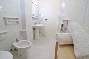 Un baño con bidé, lavamanos e inodoro.