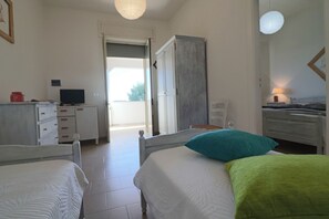 A bedroom with two beds, a desk, a television, and a wardrobe.