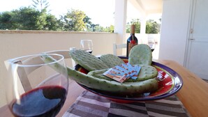 Un tavolo con un piatto di cactus fico d'India, un bicchiere di vino rosso e una bottiglia di vino.