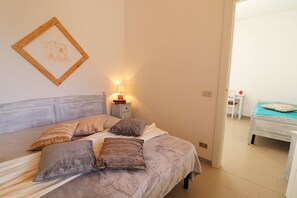 Une chambre à coucher avec un lit, des oreillers, une table de chevet avec une lampe et un tableau encadré au mur.