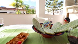 Une table avec un bol contenant un cactus, une assiette d’oignons frits et une bouteille de vin.