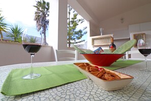 Une table avec un verre de vin rouge, un bol de nourriture et une bouteille de vin.