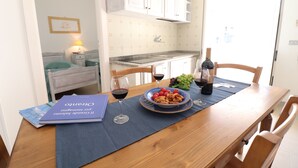 Ein Esstisch mit blauer Tischdecke, einem Teller mit Speisen, Weingläsern und einer Weinflasche.