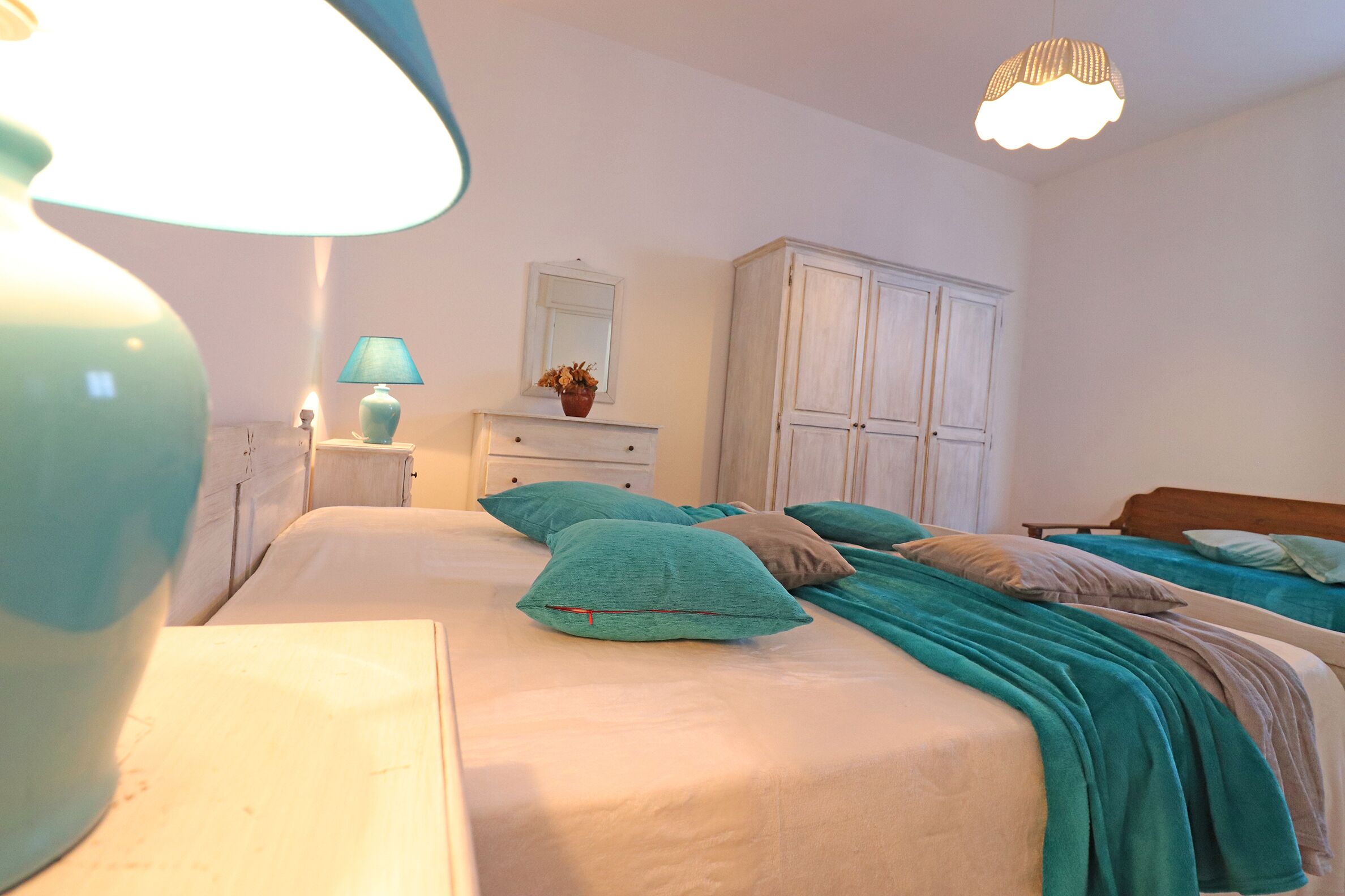 A bedroom with two beds, a nightstand, a dresser, and a mirror.