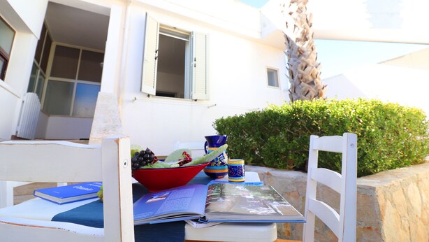 A table with a bowl of fruit, a book, and a cup.