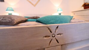 A bed with a floral design, teal pillows, and two lamps on either side.