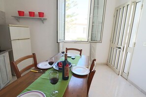 Un'area pranzo con un tavolo apparecchiato per due, una bottiglia di vino e una finestra con vista.