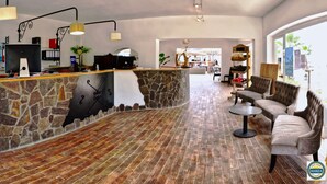 A spacious lobby with a stone reception desk, a comfortable seating area, and a view through large windows.