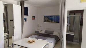 A modern bedroom with a bed, bedside tables, a desk with a bowl of food, and a painting of a coastal landscape. - Nature, Sea and Serenity Near Baia dei Turchi (Otranto)