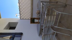 A balcony with a metal chair, a small wooden box with a plant, and a metal railing. - Nature, Sea and Serenity Near Baia dei Turchi (Otranto)