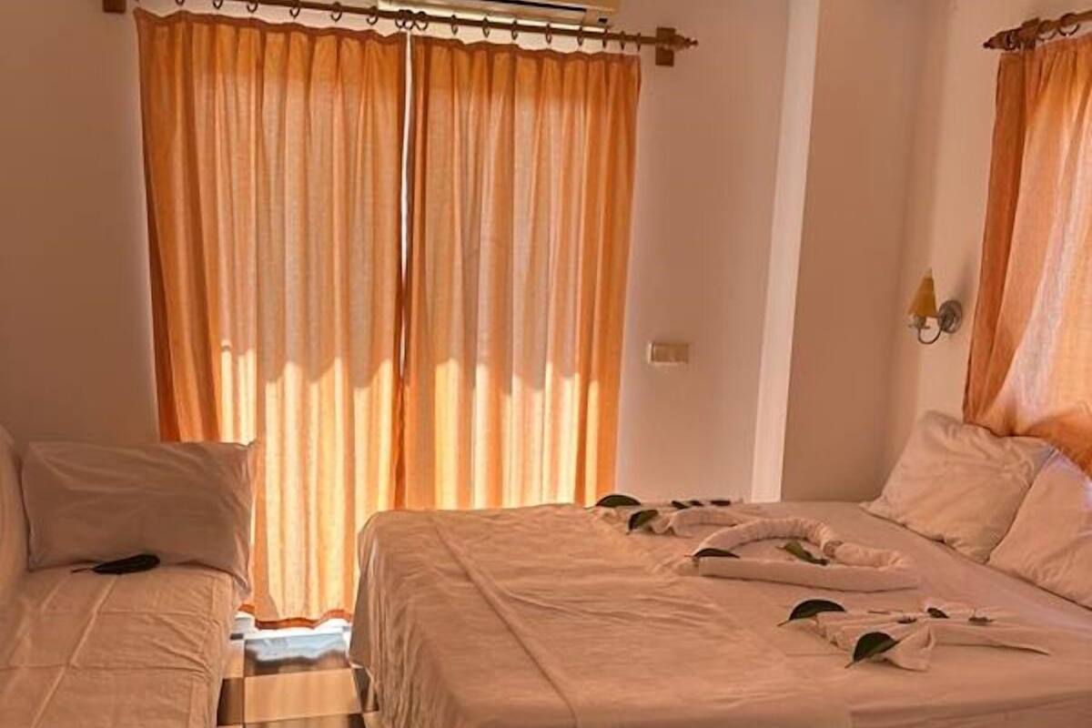 A hotel room with two beds, checkered floor, and curtains.