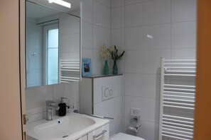 Une salle de bain moderne avec un lavabo blanc, un miroir et un porte-serviettes.