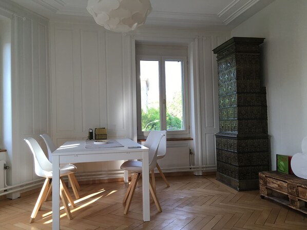 Ein Essbereich mit weißem Tisch und Stühlen, einem großen Fenster und einer dekorativen Vitrine.