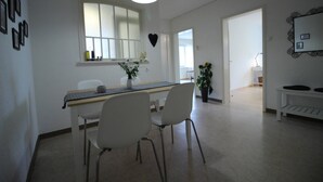 A modern kitchen with white cabinetry, a large window, and a pendant light.