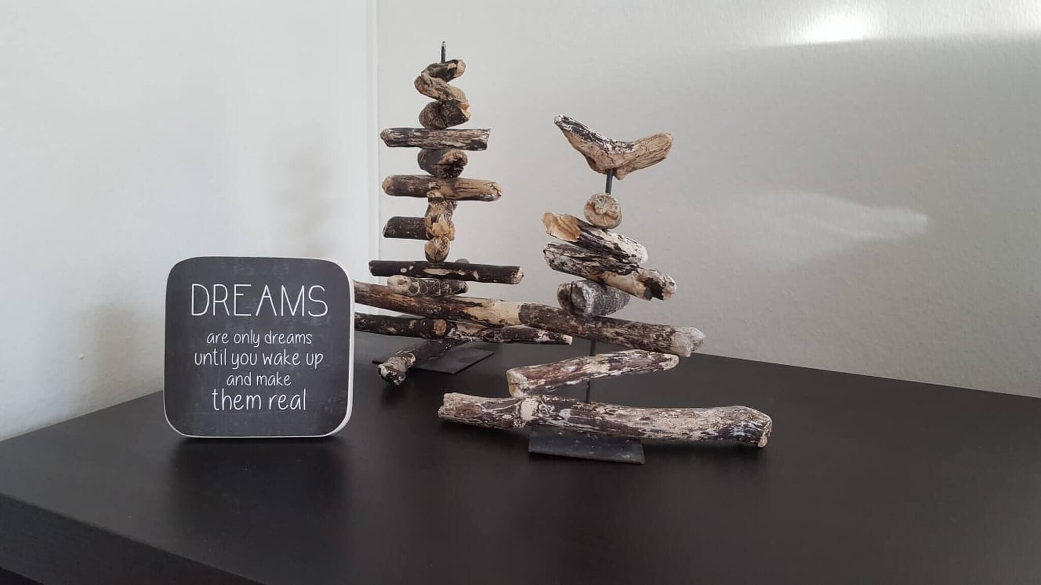 A wooden sculpture on a table with a sign that reads "DREAMS are only dreams until you wake up and make them real."