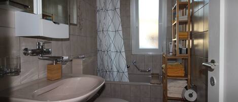 Ein Badezimmer mit Waschbecken, Toilette, Dusche und einem Fenster.