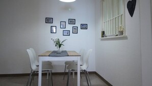A dining area with a table, chairs, a hanging light fixture, and a heart-shaped decoration on the wall.