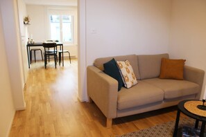 Un salon comprenant un canapé, une table basse ronde et un coin repas avec une table et des chaises.