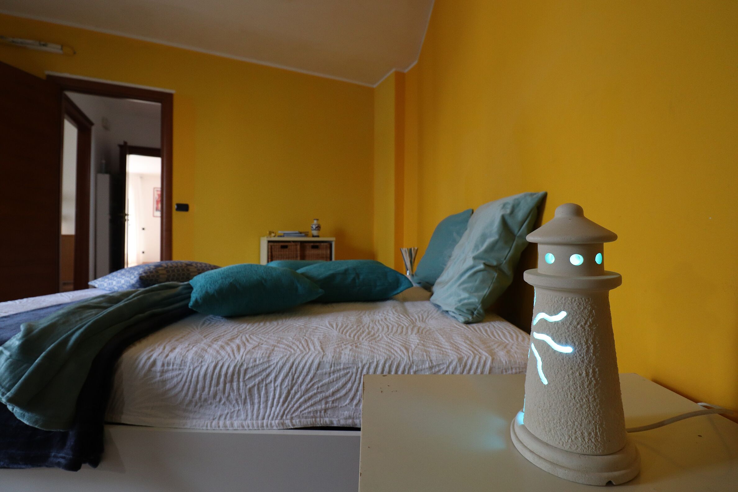 Une chambre à coucher avec un lit, des oreillers, une table de chevet et une lampe.