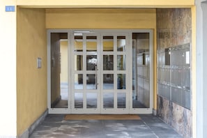 A building entrance with a glass door, a keypad, and a wall-mounted locker. - Vacation Rental Seeblick Pocobelli in Melide (Melide)