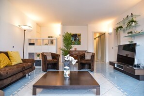 A modern living room with a sofa, armchairs, a coffee table, and a TV. - Vacation Rental Seeblick Pocobelli in Melide (Melide)