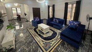 A modern living room with a marble floor, blue sofas, a white coffee table, and a patterned rug. - Immaculate 4-bed Detached Duplex in Lekki Chevron (Lekki)