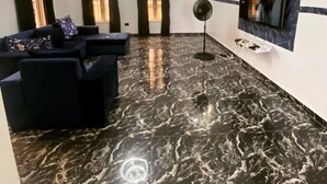 A modern living room with a marble floor, black sofas, a flat-screen TV mounted on the wall, and a ceiling fan. - Immaculate 4-bed Detached Duplex in Lekki Chevron (Lekki)